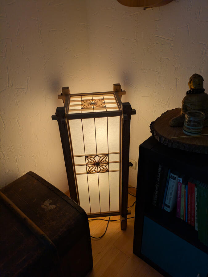 Kumiko-Stehlampe mit Asanoha-Muster, beleuchtet, in einer Zimmerecke Kumiko-Stehlampe mit Asanoha-Muster, beleuchtet, in einer Zimmerecke